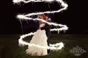 bride and groom kissing under a swirl of sparklers