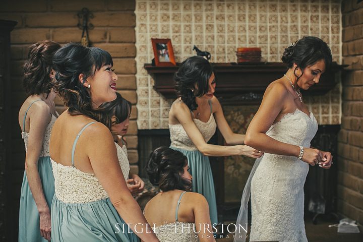 buttoning the bride into her beautiful lace wedding dress