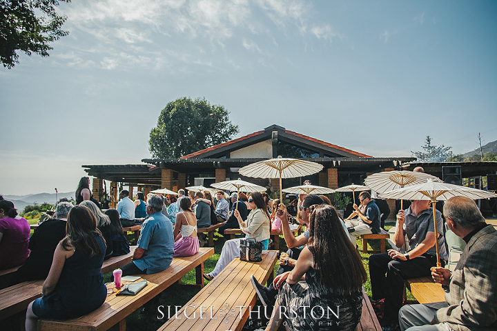 white parasols were given to the guests to keep the sun off them during the wedding ceremony