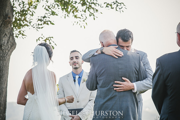 sentimental photo of the groom hugging his father in law during the wedding ceremony