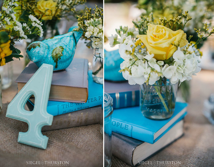 center piece consisting of mason jars, books, ceramic birds, yellow and white flowers