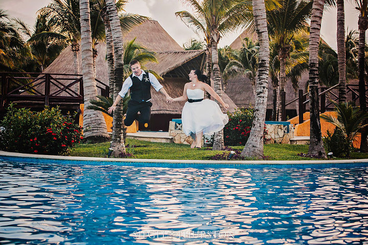 bride and groom airborne jumping into a swimming pool in their tux and wedding dress