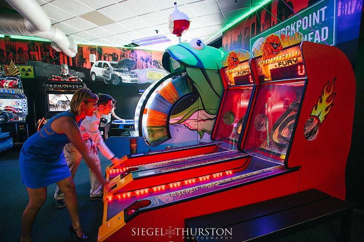 cute couple playing skeeball on their engagement shoot at belmont park in san diego