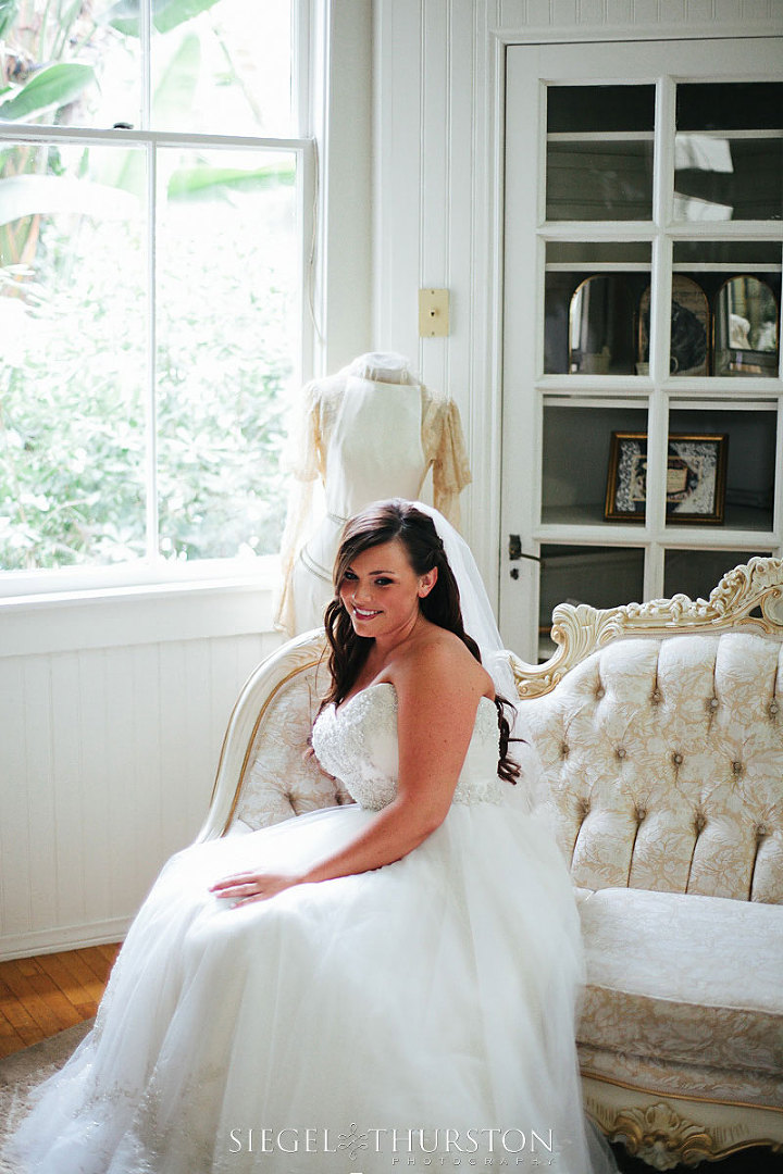 bride sitting on a beautiful vintage couch in the bridal suite at Green Gables Estates in San Diego