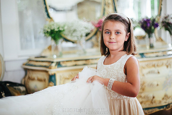 flower girl holding up the brides dress before she walks out for her wedding ceremony