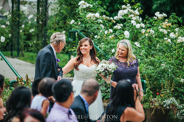 bride walking down the aisle with her mom and grandfather