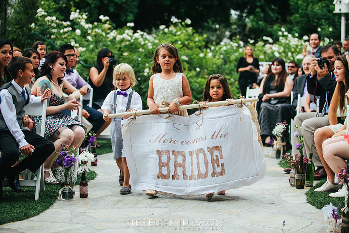 diy here comes the bride sign or flag carried by three cute children