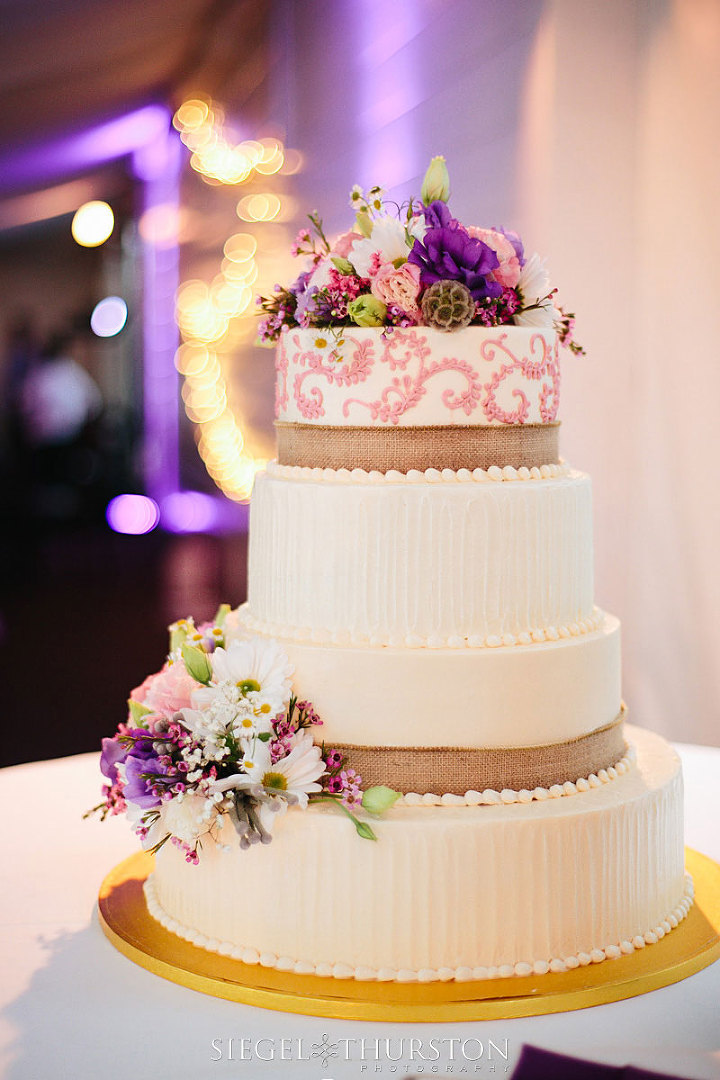 white and pink four tier wedding cake with burlap ribbon