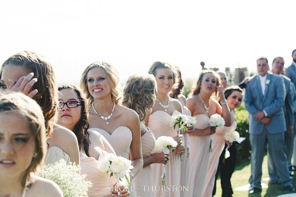 bridesmaids all trying to catch a peek at the bride as she enders the wedding ceremony