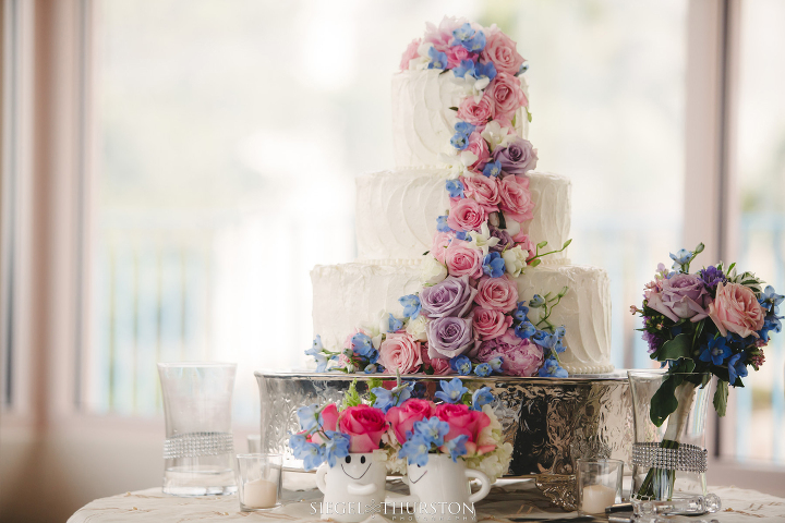 three tier white wedding cake with flowers cascading down the side 