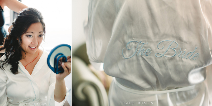 bride getting ready in a silk robe with Bride embroidered on the back in light blue