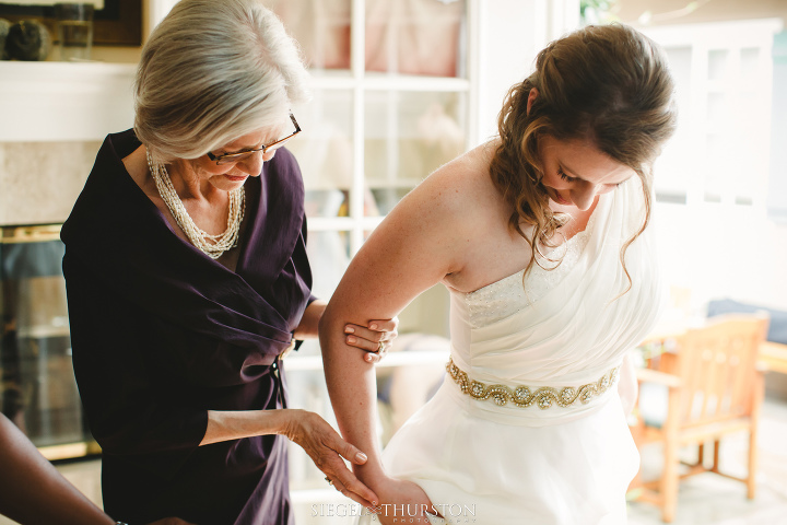 mom helping her daughter into her wedding dress