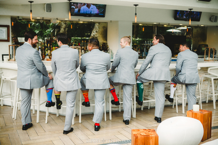 groomsmen all showing off their super hero socks at the bar
