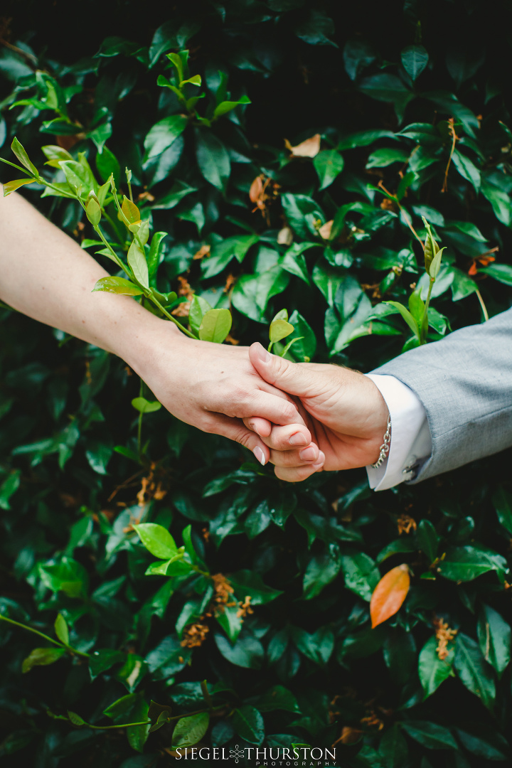 Bride and groom holding hands around a corner before their wedding ceremony but not seeing one another