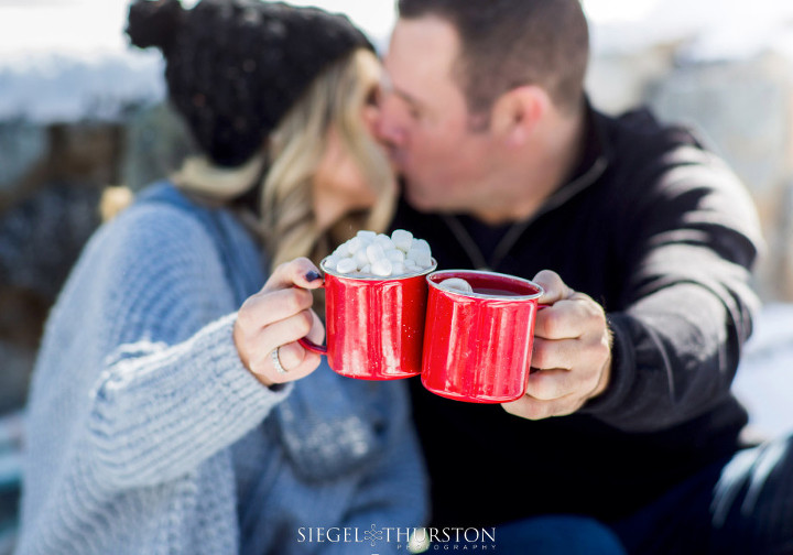 Winter engagement photos with red camping mugs and hot chocolate