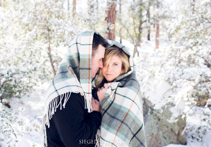 winter engagement shoot with a plaid blanket in the forest